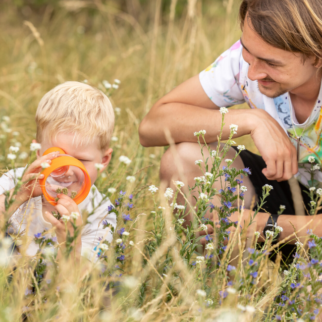 Junger Mann und Kleinkind sitzen auf Blumenwiese 