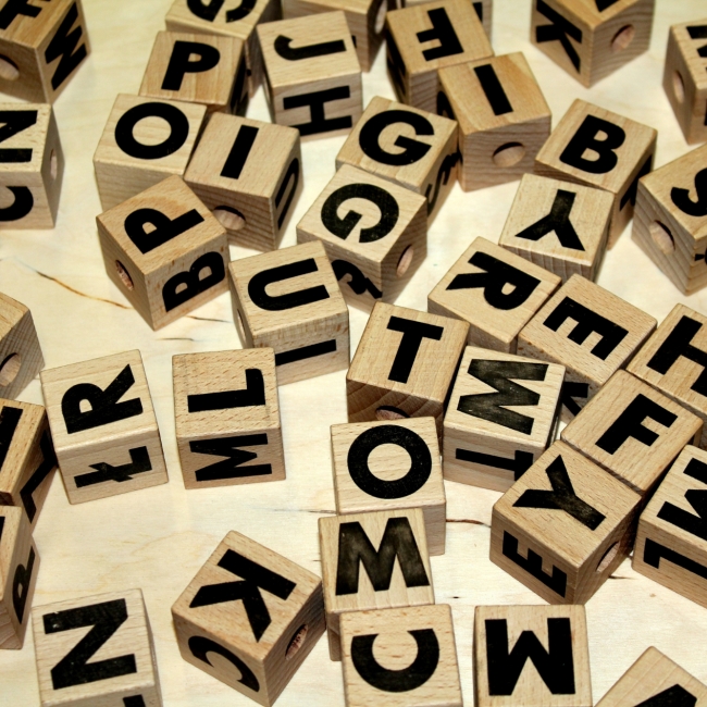 Holzwürfel mit schwarzen Buchstaben auf einem Tisch.