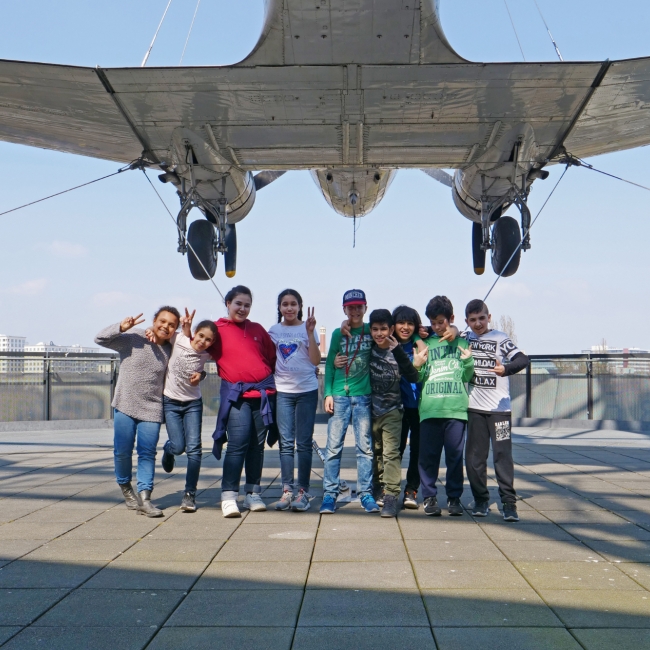 Eine Gruppe von Kindern steht unter einem Flugzeug in einem Museum in Berlin.