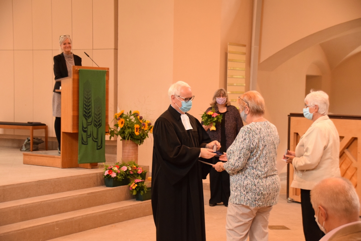Ein Pfarrer übergibt den Ehrentaler an eine ältere Frau.