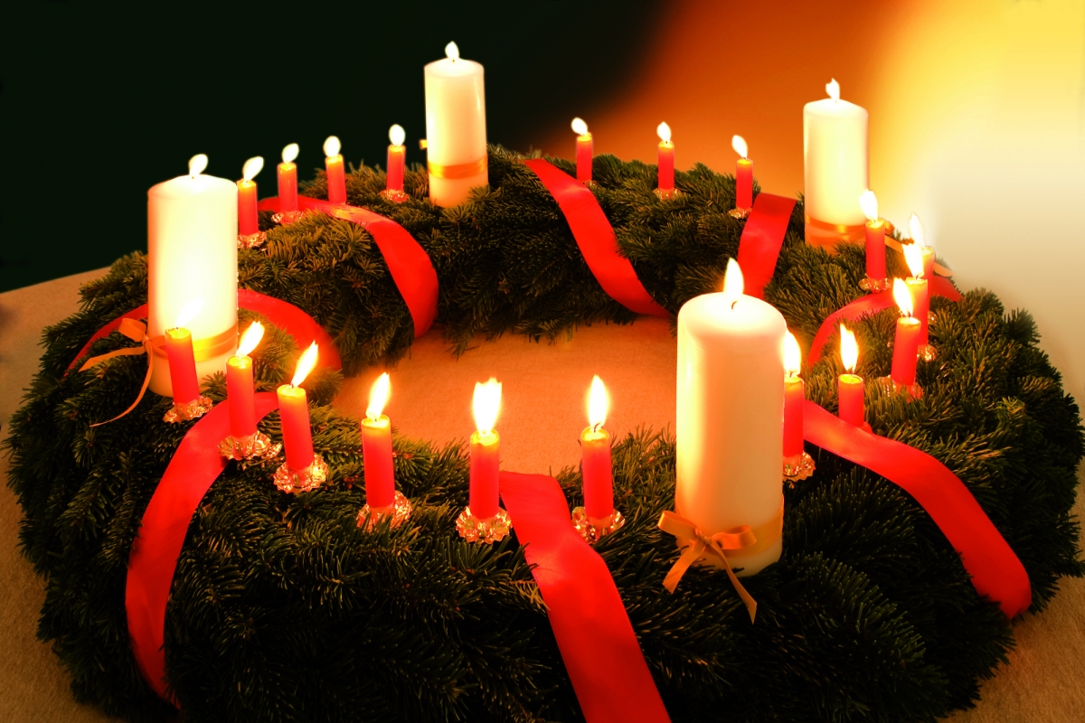 Ein Adventskranz mit vier großen Kerzen und vielen kleinen Kerzen.