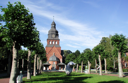 Blick über eine Allee auf die Stiftskirche auf dem Gelände des Evangelischen Johannesstifts.