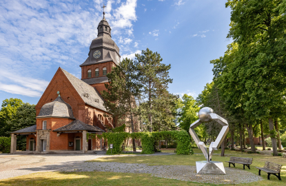 Foto der Stiftskirche von außen mit einer Skulptur an der rechten Seite 