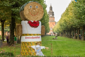Große Strohfigur auf dem Gelände des Evangelischen Johannesstifts. Im Hintergrund ist die Stiftskirche zu sehen.