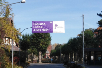 Banner über Stifteinfahrt "Glaube, Liebe, Alles drin"