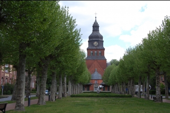 Blick über eine Allee auf die Stiftskirche auf dem Gelände des Evangelischen Johannesstifts.