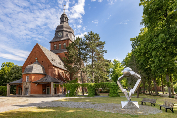 Foto der Stiftskirche von außen mit einer Skulptur an der rechten Seite 